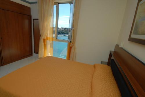 a bedroom with a bed and a large window at Hotel Baia Del Sorriso in Castiglioncello