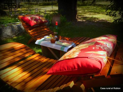a bench with two pillows and a table with a bottle of wine at Casa Rural El Roblon in Sartajada