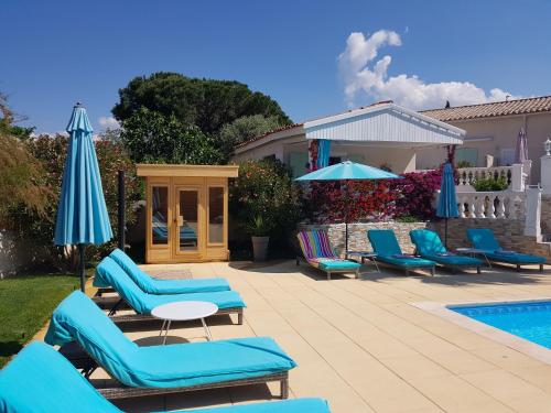 a group of chairs and umbrellas next to a swimming pool at Villa Colombier in Fréjus