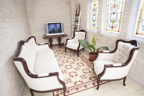 a living room with three chairs and a tv at Huis Van Gustafine Floor 2 in Malang