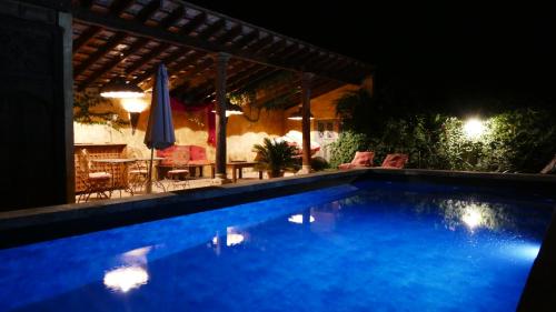 a swimming pool at night with a table and umbrella at Mas du Puits d'Amour in Orange