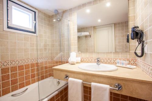 a bathroom with a sink and a bath tub at Grupotel Club Menorca in Son Xoriguer