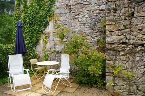 a patio with a table and chairs and a stone wall at Quercy Stone Gite Marcilhac in Marcilhac-sur-Célé