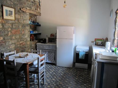 a kitchen with a table and a white refrigerator at Fig Leaf House in Elounda