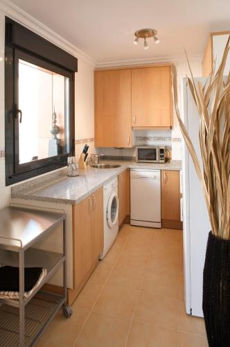 a kitchen with wooden cabinets and a white refrigerator at Ático con amplia terraza Nautilus II - VUT-480-AS in Luanco