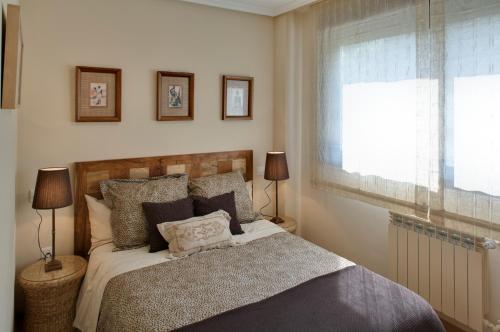 1 dormitorio con 1 cama con 2 lámparas y una ventana en Ático con amplia terraza Nautilus II, en Luanco