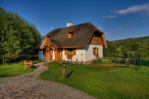 una casa con techo de paja en un campo en Hotel Osada Karbówko Wellness & SPA, en Elgiszewo