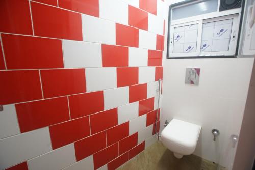 a bathroom with a toilet and a red and white tile wall at Mumbai Staytion Dorm- Hostel in Mumbai