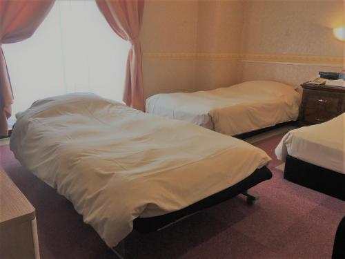two beds in a hotel room with white sheets at Business Hotel La Firenze in Tokyo