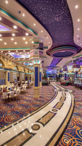 a hotel lobby with tables and chairs and purple ceilings at Merit Grand Mosta Spa Hotel & Casino in Svilengrad