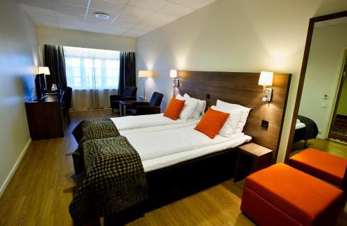 a hotel room with a large bed with orange pillows at Thon PartnerHotel Baronen in Ålesund