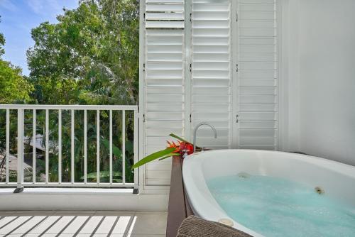 a bath tub in a room with a balcony at Palm Cove Paradise - Couples spa beach getaway in Palm Cove