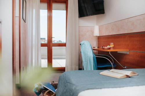 a hotel room with a bed and a desk and a table at Hotel Argentina in Grado