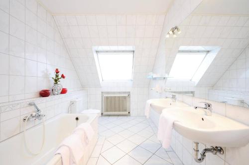 een witte badkamer met 2 wastafels en een bad bij Hotel am Markt in Fürstenau