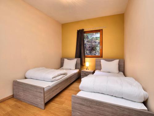 Cette chambre comprend 2 lits dans une chambre dotée de murs jaunes et d'une fenêtre. dans l'établissement Charming Holiday Home In Durbuy with Garden, à Verlaine