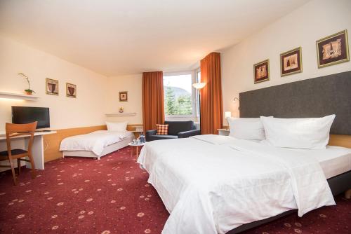 a hotel room with two beds and a desk at Akzent Hotel Höhenblick in Mühlhausen im Täle