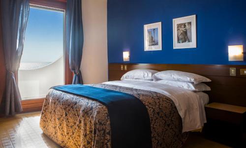 a bedroom with a large bed with a blue wall at Hotel Sinuessa Terme in Mondragone