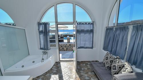 uma casa de banho com banheira e uma grande janela em Thirassia Paradise Suites em Thirasía