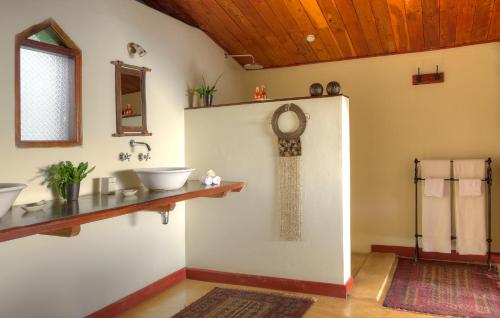 a bathroom with two sinks and a clock on the wall at Entumoto Main Camp in Ololaimutiek