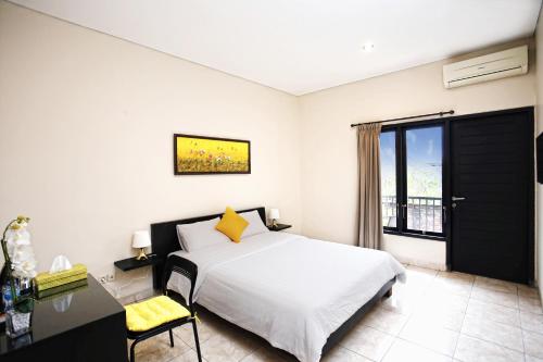 um quarto com uma cama, uma secretária e uma janela em Cameng Homestay em Denpasar