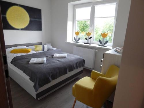 a bedroom with a bed and a yellow chair at Apartament Malwina in Polanica-Zdrój