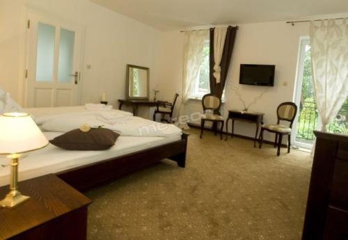 a bedroom with a bed and chairs and a television at Rewa in Rewal