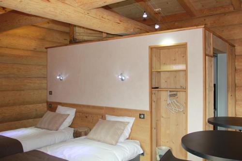 two beds in a room with wooden walls at Les Chalets de Maramour in Chazey-sur-Ain