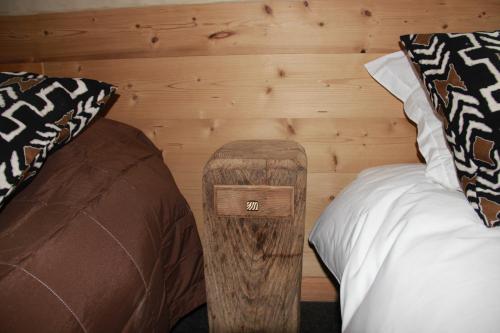 a room with two beds and a wooden wall at Les Chalets de Maramour in Chazey-sur-Ain