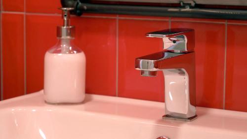 un lavandino in bagno con una bottiglia di sapone accanto a un rubinetto di Cardìlle Apartment a Monopoli