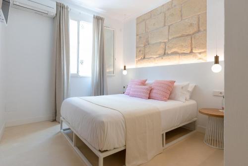 a white bedroom with a white bed with pink pillows at LLONGA'S 11th in Ciutadella