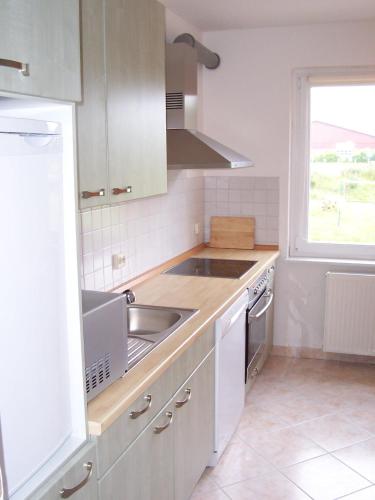 a kitchen with white cabinets and a sink and a window at Haus Marinus in Puttgarden