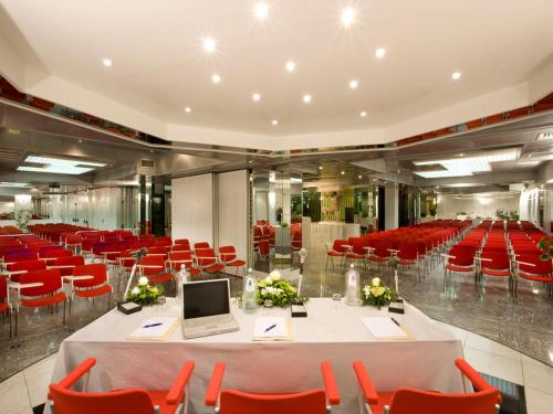 a conference room with red chairs and a table with a laptop at Hotel Savoy in Pesaro