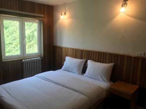 a bedroom with a white bed with two pillows and a window at CentreToni Arida in Al Arz