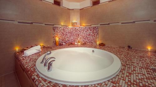 a bathroom with a large tub with candles in it at Kobuleti Georgia Palace Hotel & Spa in Kobuleti