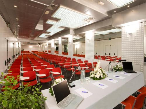 a conference room with a long table and red chairs at Hotel Savoy in Pesaro