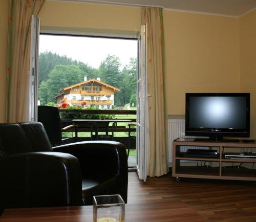 een woonkamer met een televisie en een groot raam bij Ferienwohnungen Martinsklause in Ramsau