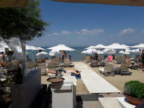 a beach with people sitting in chairs and umbrellas at Cabo Verde in Agia Triada