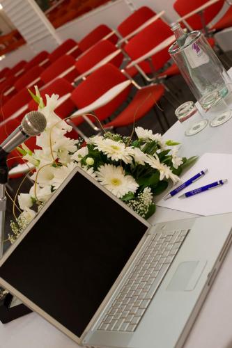 a laptop on a table with flowers and a microphone at Hotel Savoy in Pesaro