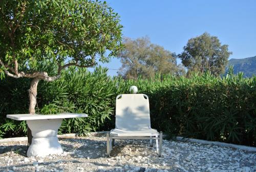 a white chair and a table in front of a hedge at Kokalakis Hotel in Kefalos