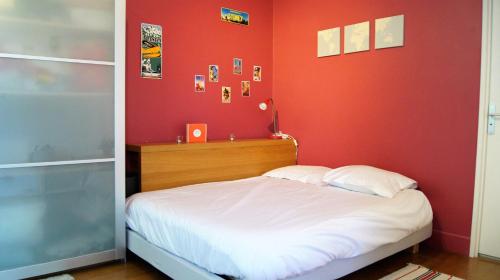 - une chambre avec des murs rouges et un lit avec des draps blancs dans l'établissement Appart Hôtel Lille LOUIS, à Lille