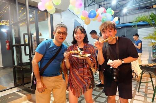 a group of three people eating a plate of food at The August Hostel in Chiang Mai