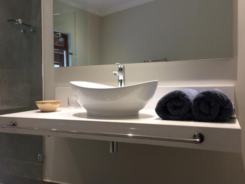 ein Badezimmer mit einem Waschbecken, einem Spiegel und Handtüchern in der Unterkunft Fish Eagle Lodge in Knysna