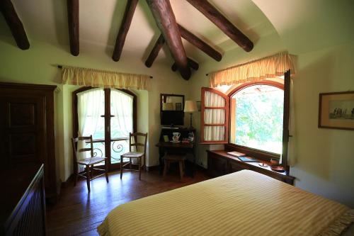 a bedroom with a bed and a desk and two windows at The Golf Club Guest House in Menaggio