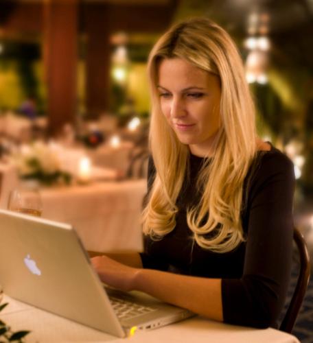a woman sitting at a table using a laptop computer at Hotel Savoy in Pesaro