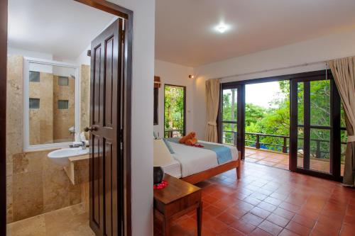 a bedroom with a bed and a bathroom with a sink at Villa Yao Yai in Choeng Mon Beach