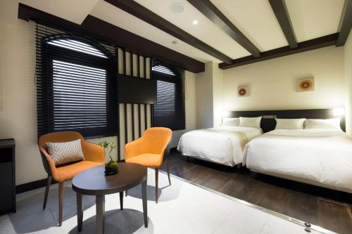 藤沢市にあるEN HOTEL Fujisawaのベッド2台とテーブルと椅子のある寝室
