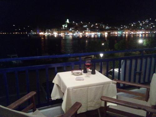 a table with a glass of wine on a balcony at night at Bissias Guest House in Galatas