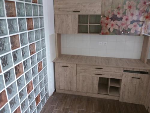 a kitchen with wooden cabinets and a tile wall at Apartament lux Albert in Olimp