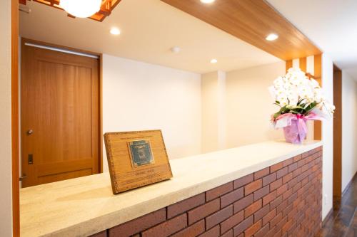 a sign on a counter with a vase of flowers at Wright Style in Naoshima