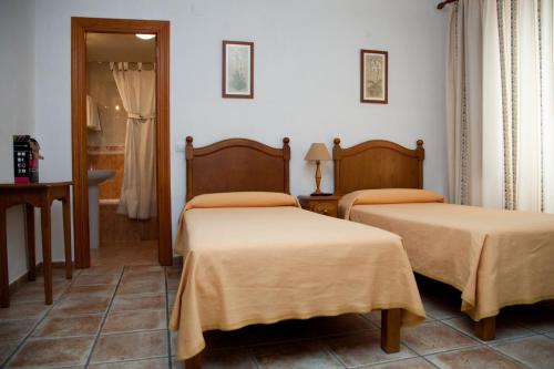 Habitación con 2 camas y espejo. en Hostal El Rincón, en Ávila